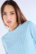 Close up of light blue cable knit sweater texture for women